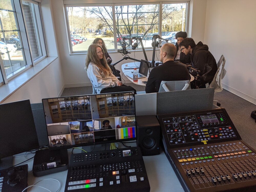 The studio has a computer desk for controlling the podcast shows, as well as cameras linked to each microphone.