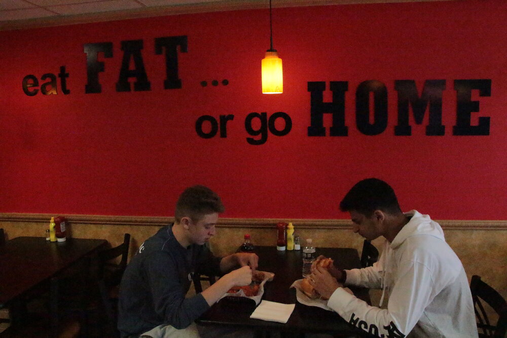 Two customers enjoying wings and a fat sandwich.