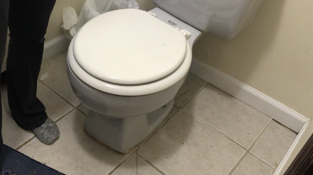 A toilet at a New Road home that appears to be sinking into the bathroom floor.