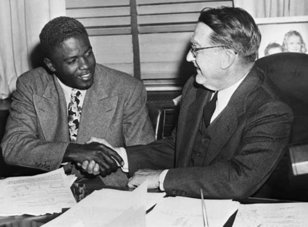 Jackie Robinson and Brooklyn Dodgers general manager Branch Rickey shake hands after agreeing to a contract back in 1948.