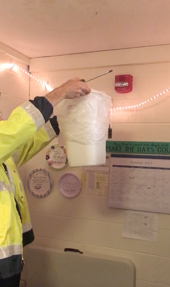 A Facilities worker holds a bucket up to a leaking roof in the Dana Residence Hall.&nbsp;