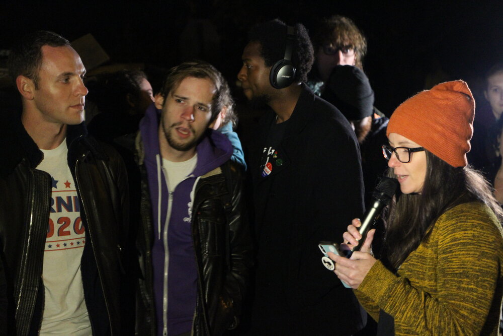 Cassie Meyerhoffer speaking to the crowd in front of Leng’s house. Left to right: Zach Carter, protestor, Justin M. Farmer. Photo by Bryan Proctor.