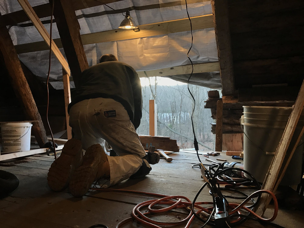 Roofer Bob Zoni gathers his tools underneath a tarp where the house’s roof once was.