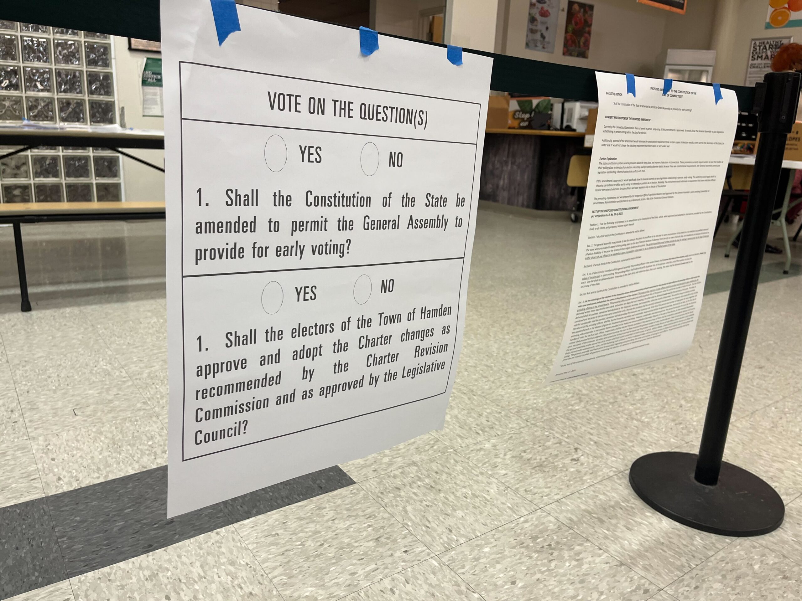 Posted questions included on the 2022 midterm election ballot. "Vote on the question(s): 1. Shall the Constitution of the State be amended to permit the General Assembly to provide for early voting? 1. Shall the electors of the Town Hamden approve and adopt the Charter changes as recommended by the Charter Revision Commission and as approved by the Legislative Council?"