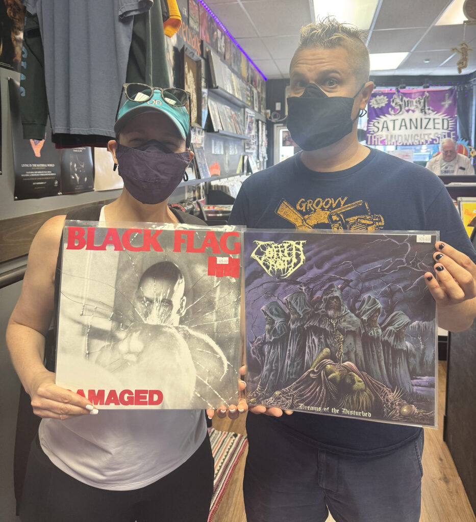 Aaron Grant holds a copy of  Dreams of The Disturbed by Coffin Rot as Rachel Scherer holds a copy of Damaged by Black Flag. (Photo by Hailey Keel)