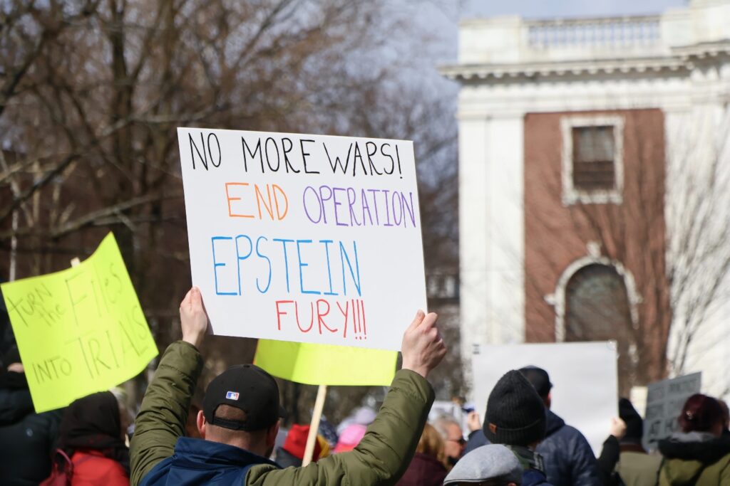A sign reads “No more wars, end Operation Epstein Fury,” referencing the U.S. military campaign against Iran known as Operation Epic Fury. Hannah Freshman/HQNN