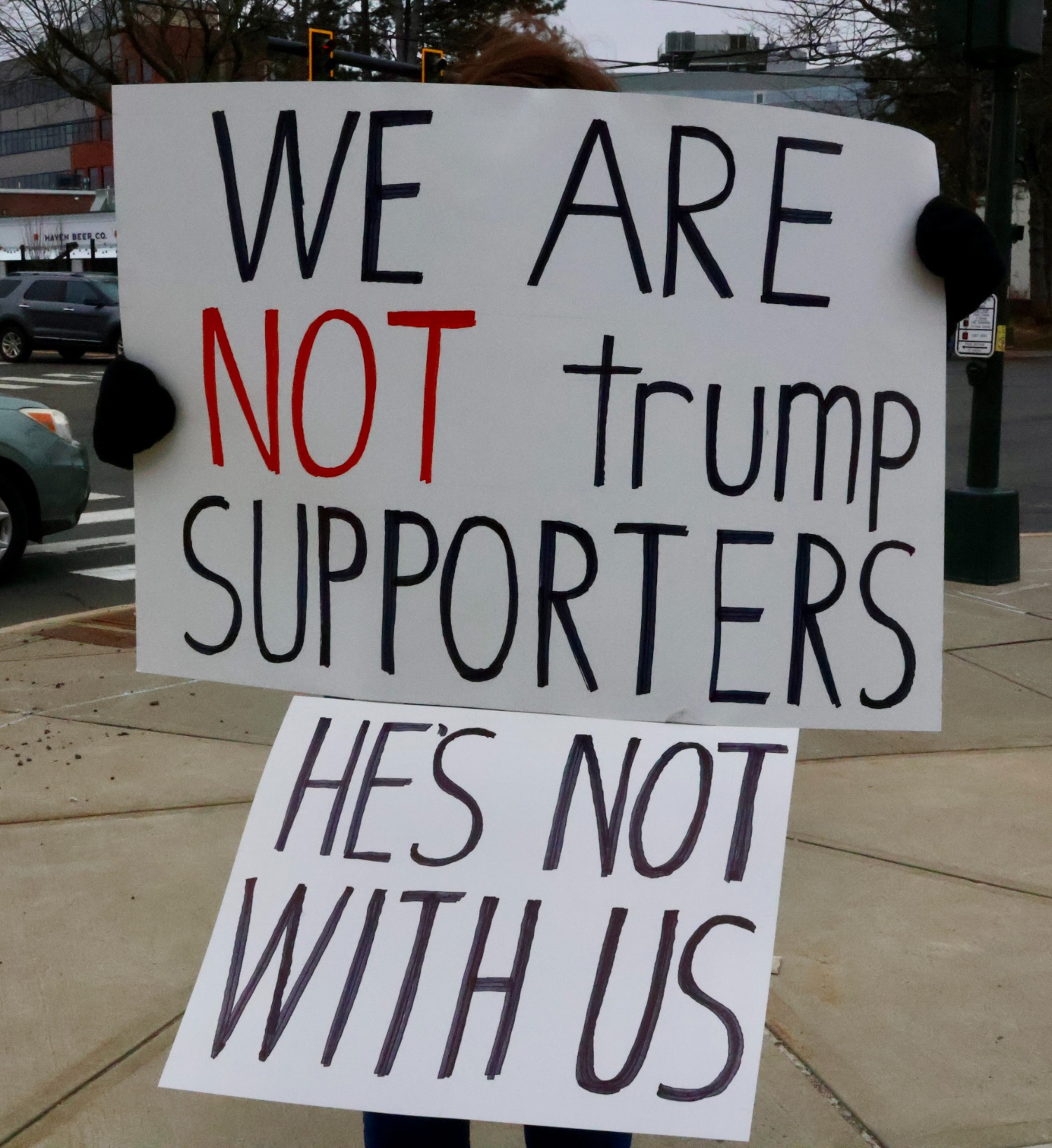 A protester holds a hand-made sign reading, “We are not Trump supporters, he’s not with us,” as demonstrators aim to distinguish their group from counter-protester Robert Vardaro. Hannah Freshman/HQNN