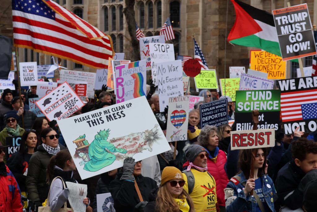 Signs raised high above a dense crowd at the “No Kings” protest in New Haven, CT. Hannah Freshman/HQNN