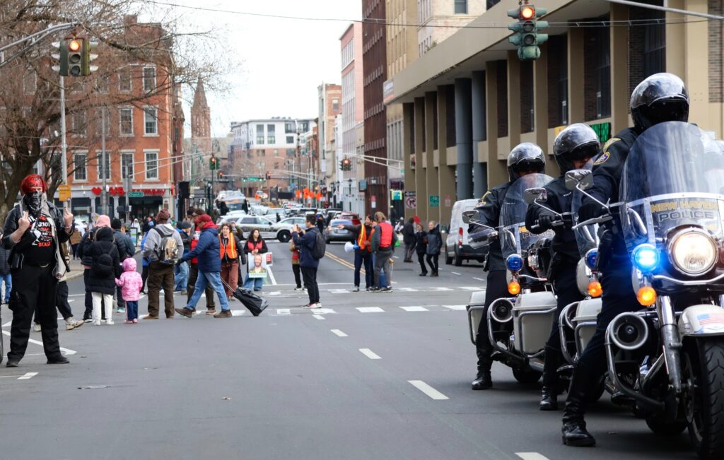 An unidentified protester makes an obscene gesture towards New Haven police as they lead the march at its start. Hannah Freshman/HQNN
