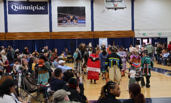 A diverse crowd of onlookers watches Indigenous dancers during the second annual Powwow. Originally planned for the Mount Carmel quad, the 2026 ceremony served as a powerful reminder of the community's shared commitment to inclusion, regardless of the setting. Hannah Freshman/HQNN