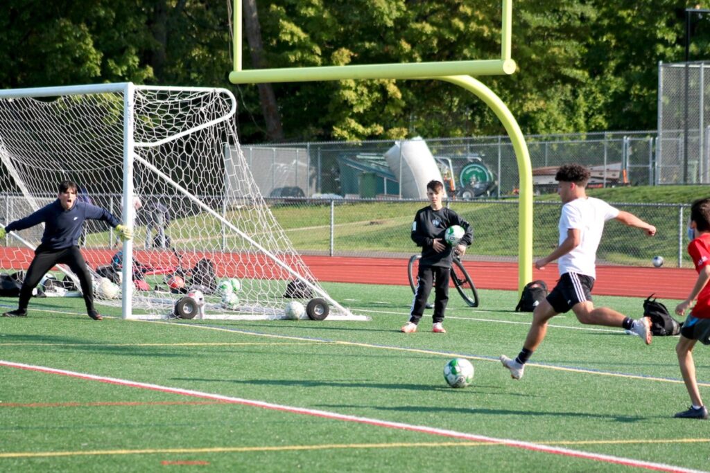 Senior right wing Josh Venditto crosses the ball to a teammate. Venditto, a Hamden High School boys varsity soccer player, faced the junior varsity team in practice.