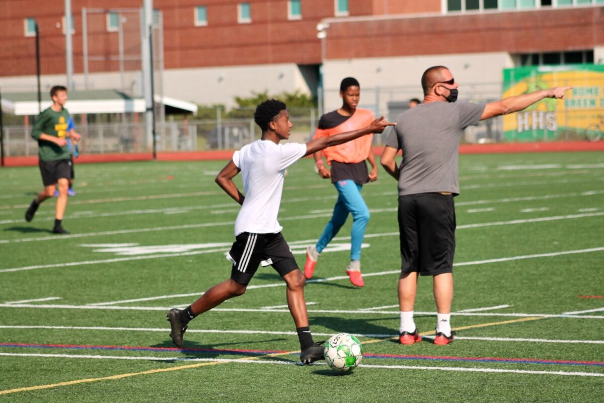 Senior midfielder Kobe Gordon dribbles up field during the Hamden High School boys varsity versus junior varsity soccer scrimmage. Varsity head coach Ralph Romano directs the team to move forward. (Photo by Brendan O'Sullivan)