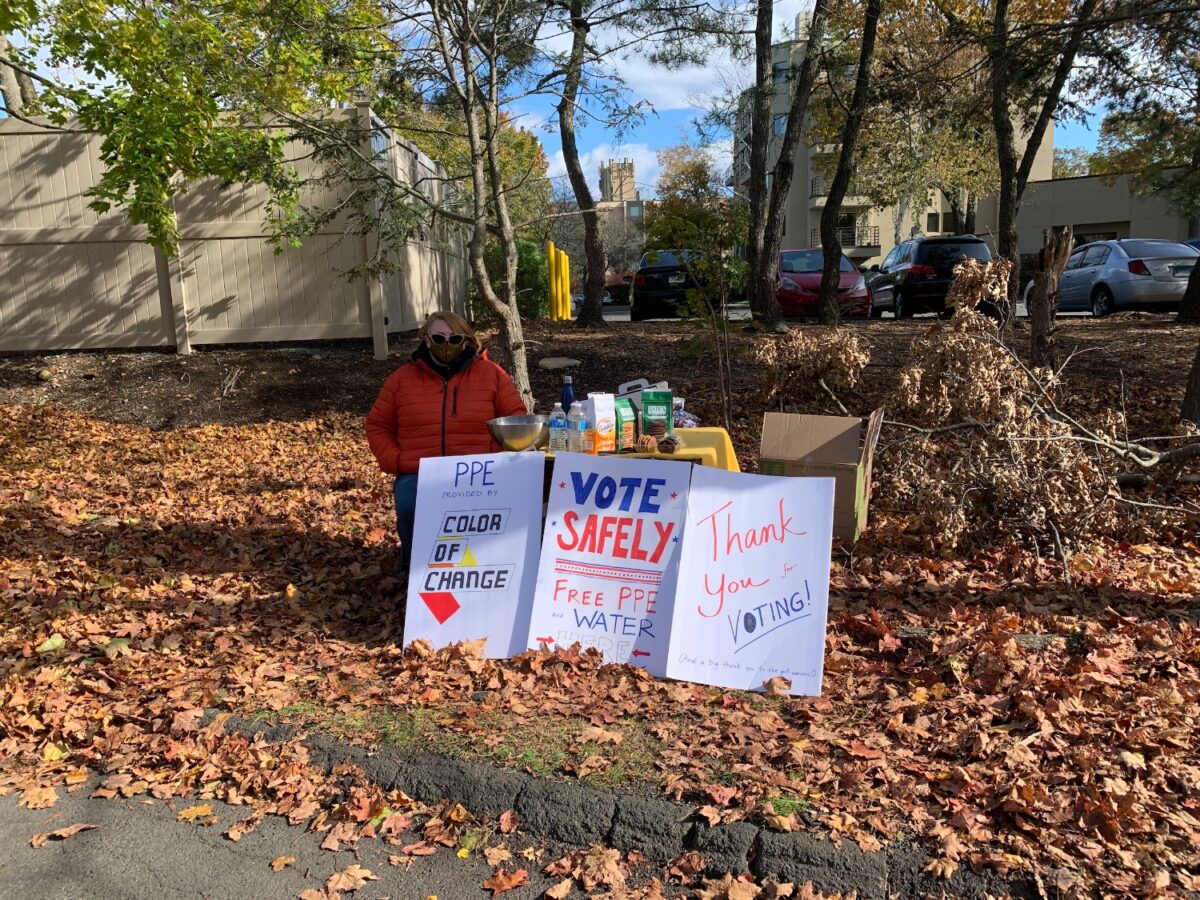 Hamden resident Emily Drennan hands out free water and PPE to voters.