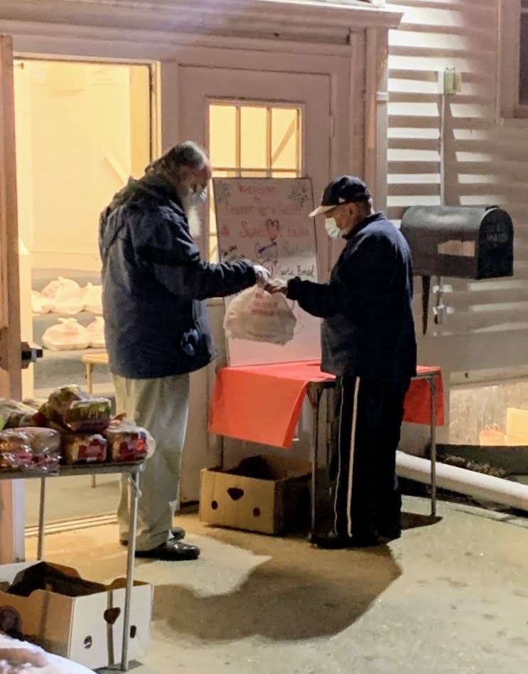 Volunteer handing out food for D4$ outside of Grace & St. Peter's Church. Photo courtesy of Bob Bergner.