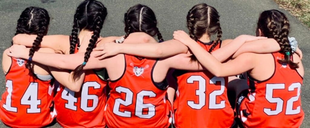 Allie Grove, 14 (far right, number 52) hugs her lacrosse teammates before the pandemic began. Photo provided: Melinda Grove