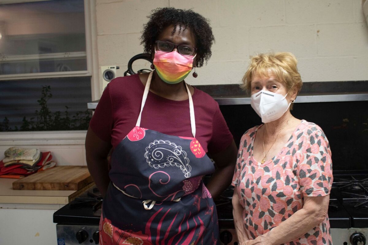 Founder of 'Dinner for a Dollar', Allison Batson and long time volunteer, Mary Ellen Porcelli, stand smiling under their masks in the church's kitchen after providing dinner for hundreds Friday night.