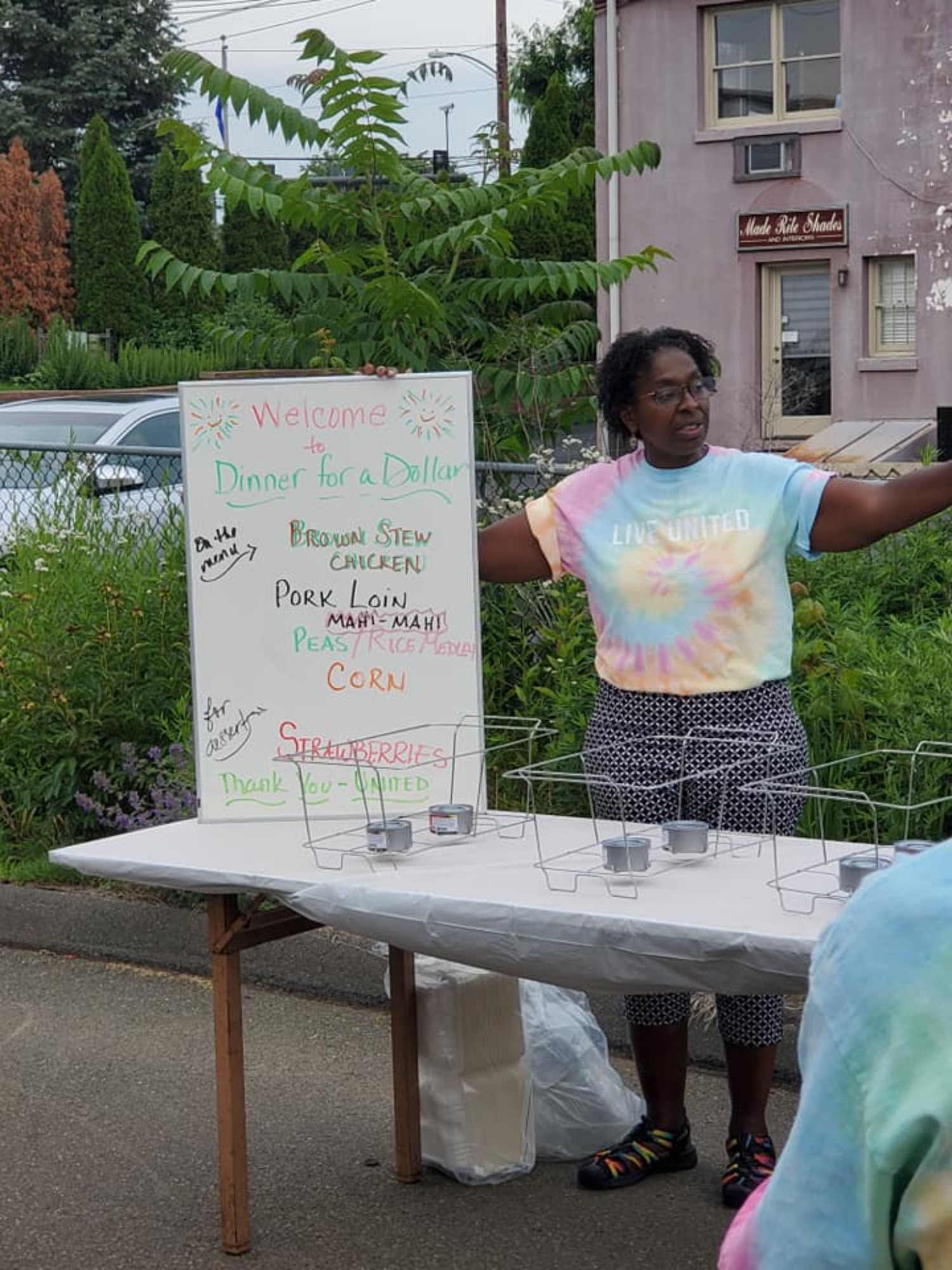 Allison Batson, founder of Dinner for a Dollar, standing with the menu and getting ready to welcome people to dinner on a Friday night this summer.