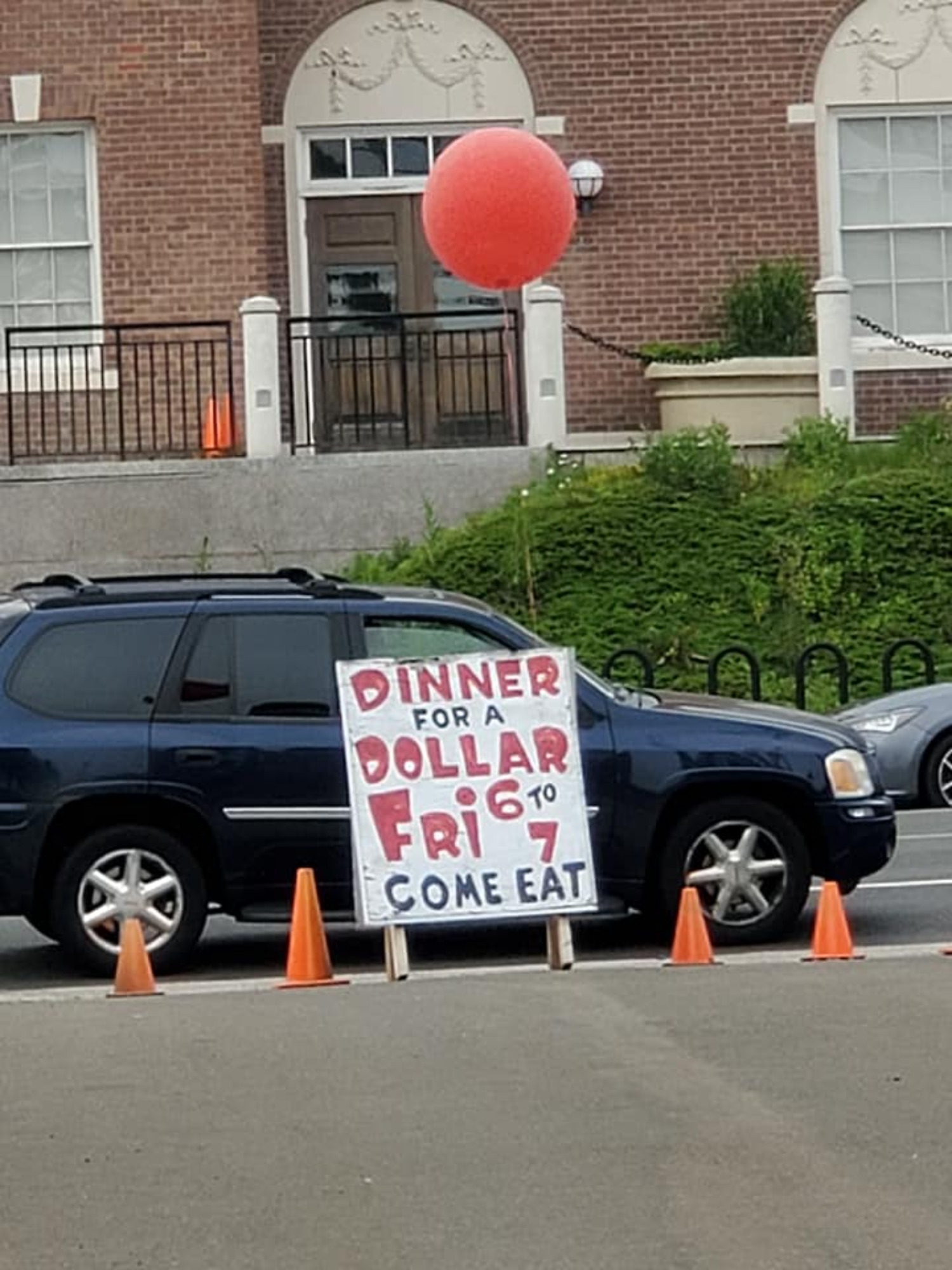 People drive by the "Dinner for a Dollar" sign that invites everyone to come eat and enjoy a home-cooked meal and company every Friday at 6 pm at Grace & St. Peter's Episcopal Church on Dixwell Ave.