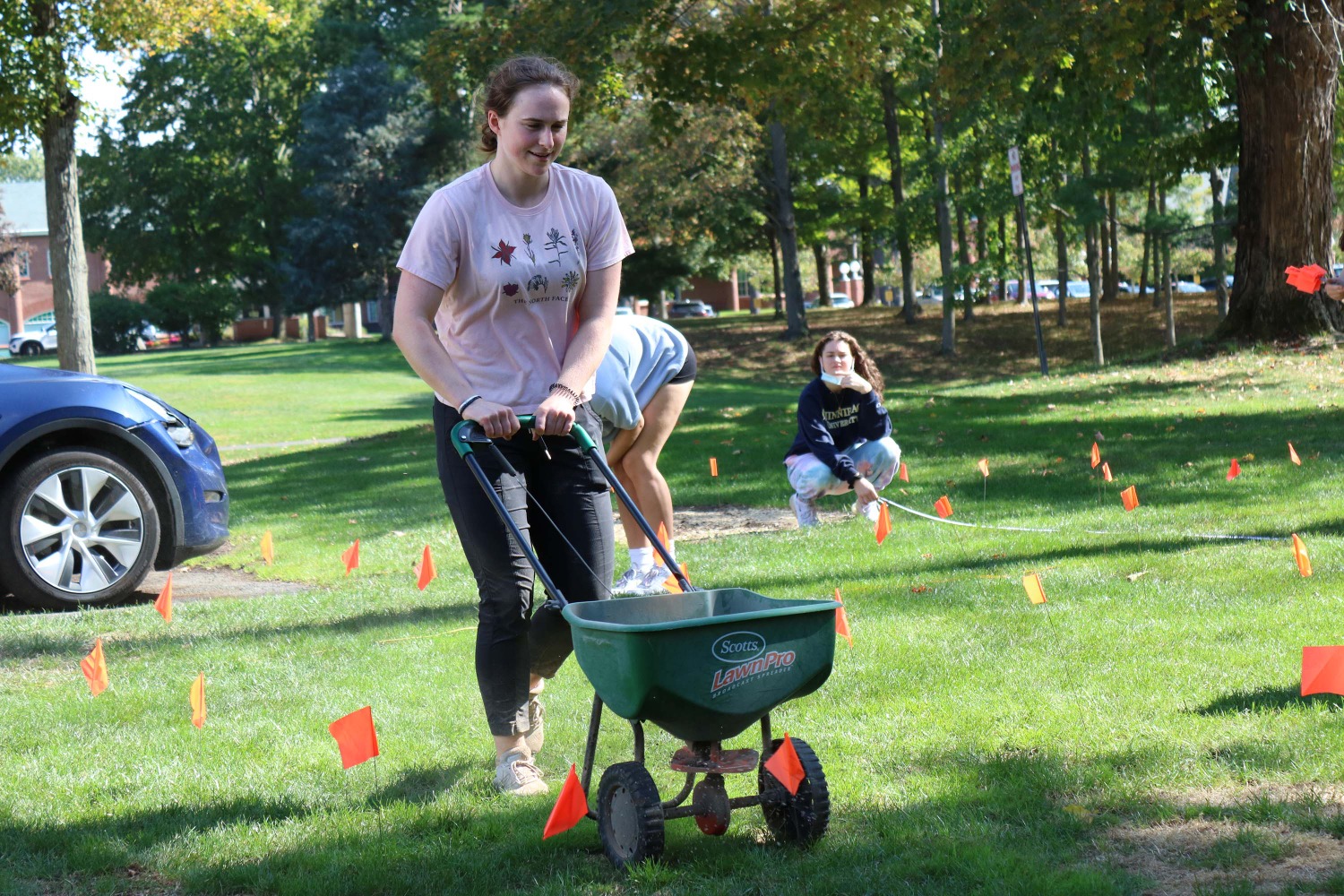 Junior Kate Reilly pushes a wheelbarrow filled with limestone, which helps neutralize the acidity of the soil, across the grid garden layout. (Photo by Michael Sicoli)
