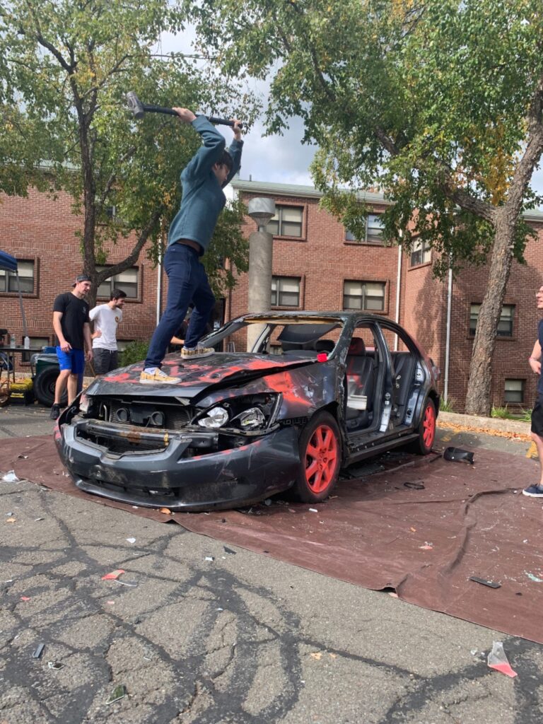 Student Sam Grauman gets on the hood to smash the dash - Photo by Alena DeLuise