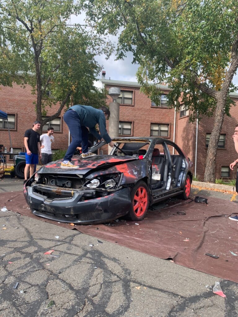 Student Sam Grauman gets on the hood to smash the dash - Photo by Alena DeLuise