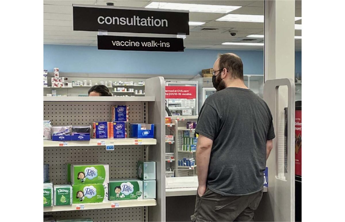 Man at CVS waiting at the counter for vaccination shot.