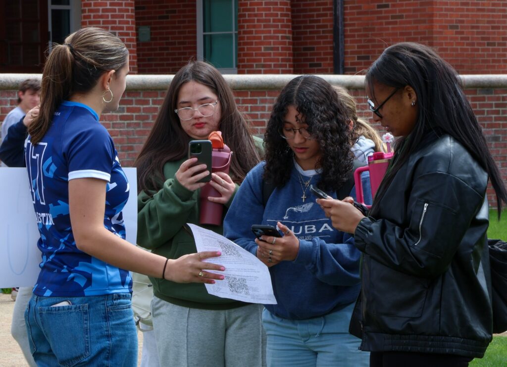 Junior lock Samantha Agostin walks aroung the crowd after the Title IX protest asking people to sign the team's petition. 